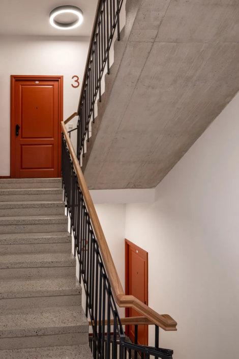 Interiérové dveře Internal Door, bytový dům Musilkova – schodiště s pohledovým betonem a červenými dveřmi bytu